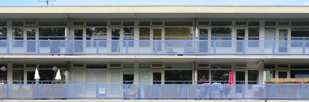 Appartementen met witte kozijnen en deuren, een balkon met een blauw hekje.