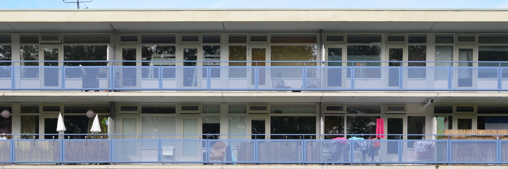 Appartementen met witte kozijnen en deuren, een balkon met een blauw hekje.