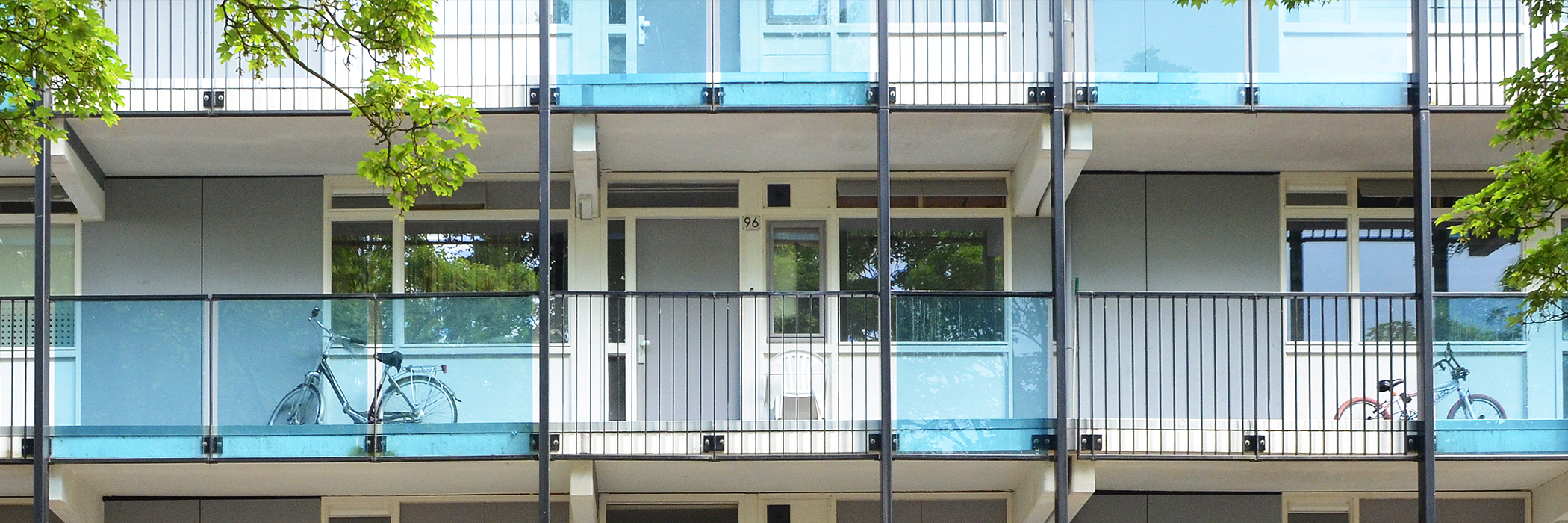 Appartementen met grijze gevel, witte kozijnen, grijze deuren met een glazen blauwe balustrade