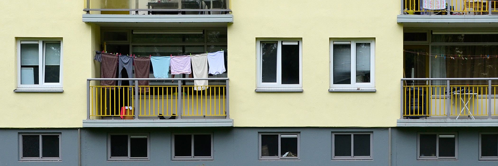 Appartementen met gele gevel, witte kozijnen, grijze balustrades en een waslijn