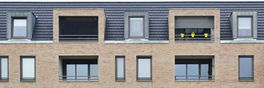 Appartementen met bruine bakstenen gevel, grijze kozijnen en balustrades