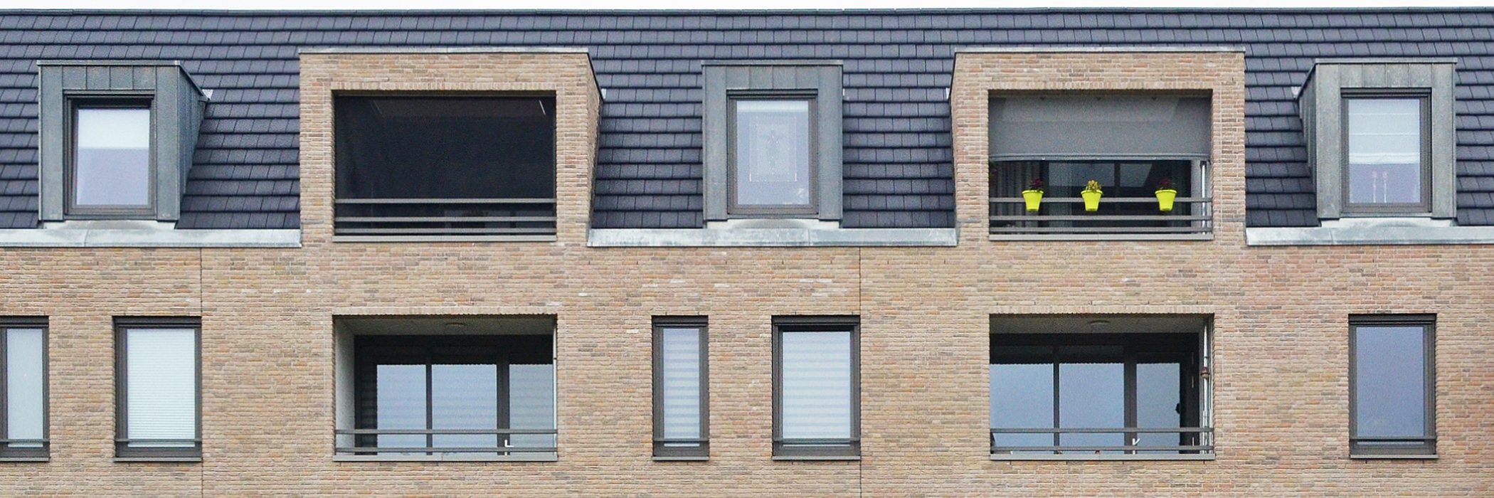 Appartementen met bruine bakstenen gevel, grijze kozijnen en balustrades
