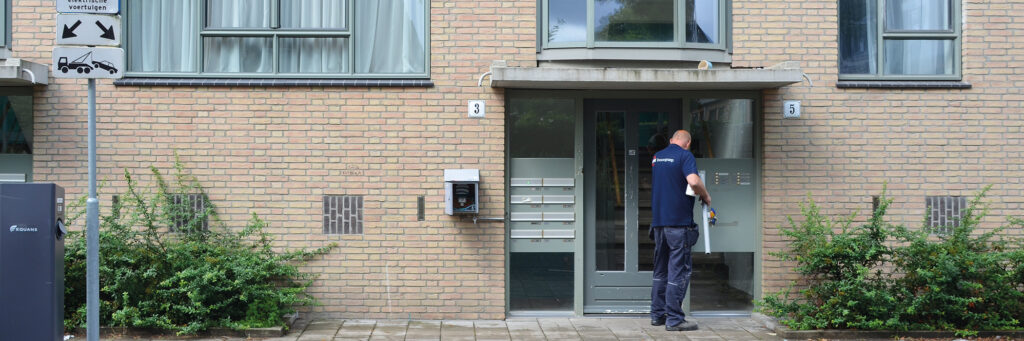 entree van een woningcomplex met elektrische laadpalen ervoor
