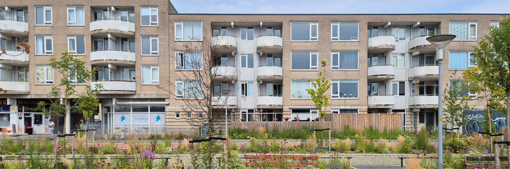 appartementencomplex met balkons. ervoor is een groenstrook te vinden met kleurrijke bloemen