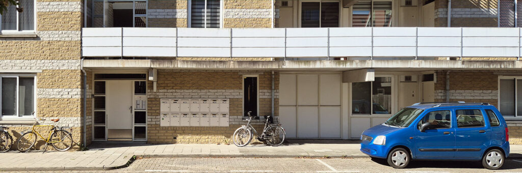 flatgebouw met ervoor een blauwe auto