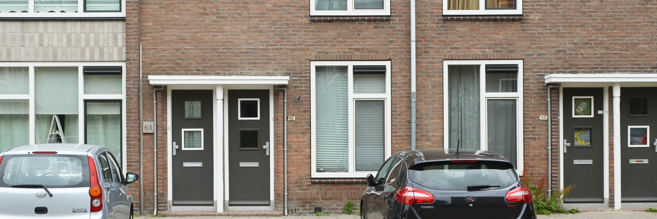 rijtjeswoningen met grijze deuren en witte kozijnen. voor de woningen is parkeergelegenheid