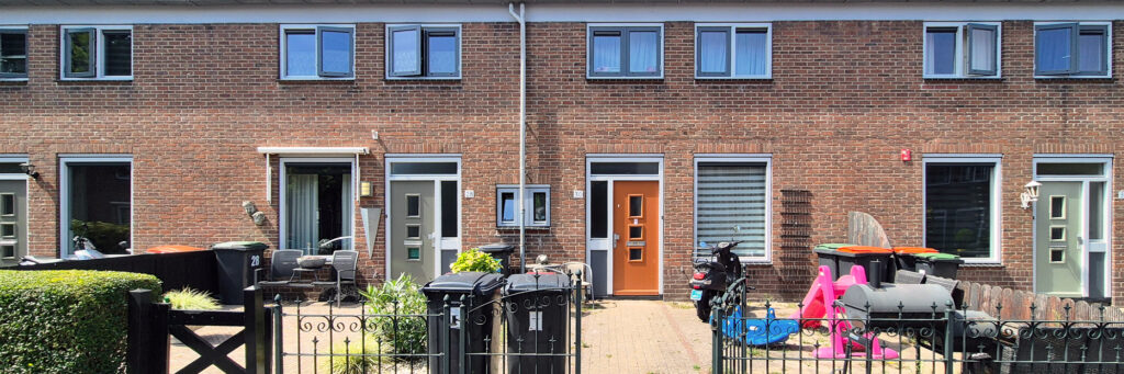 rijtjeswoningen met een grote voortuin gevuld met verschillende dingen. de ene tuin heeft een bbq en een scooter en de andere zitplaatsen en containers