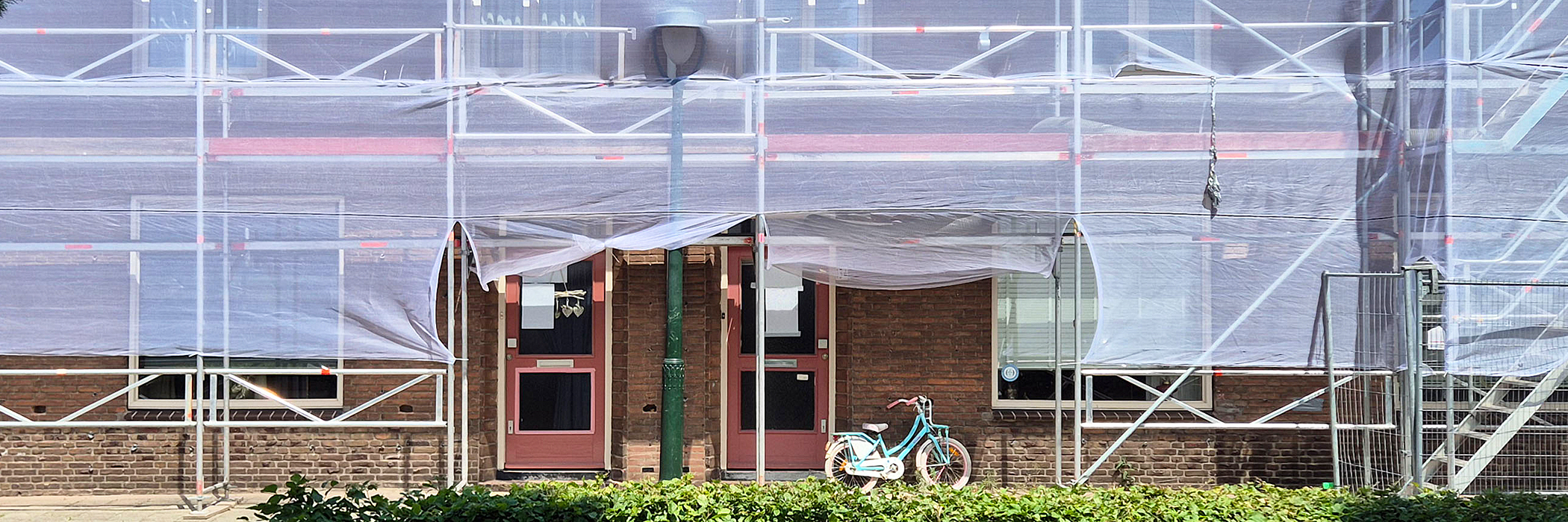 Woningen die worden verbouwd, het complex staat in de stijgers. en voor de deur staat een kinderfietsje