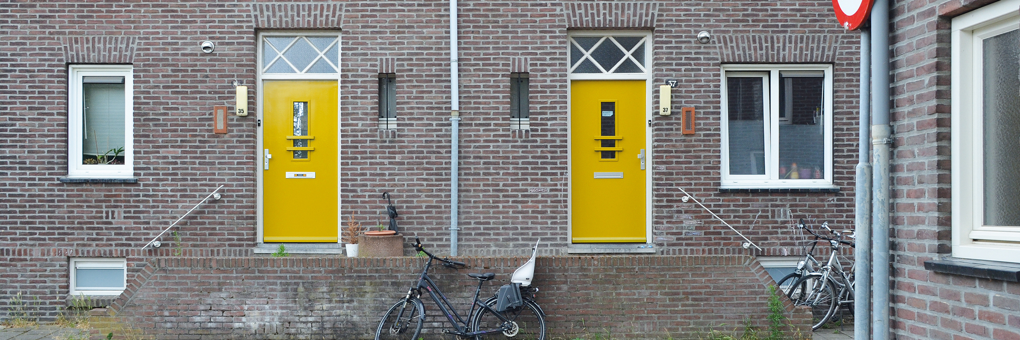 verhoogde entree voor twee woningen met gele deuren