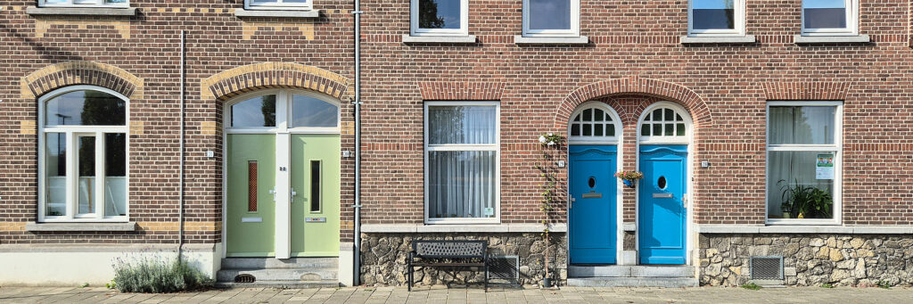 Schakelwoningen met een boog boven de entree. aan de linkerkant groenen deuren aan de rechter kant blauwe deuren