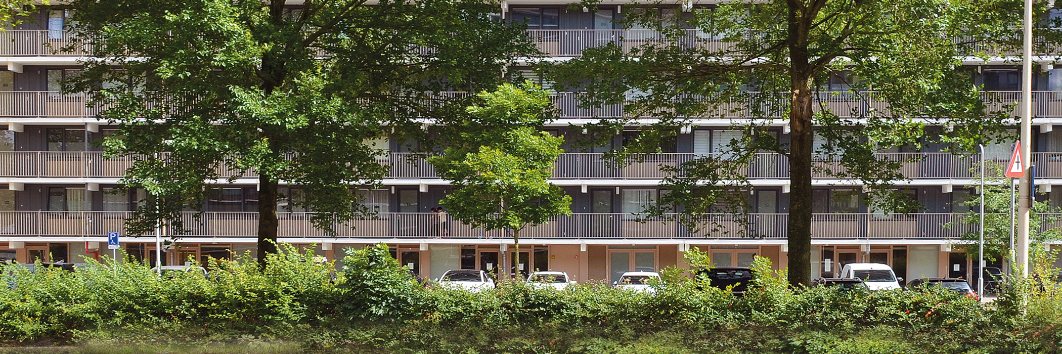 Flat met hele grote bomen en groenstrook ervoor