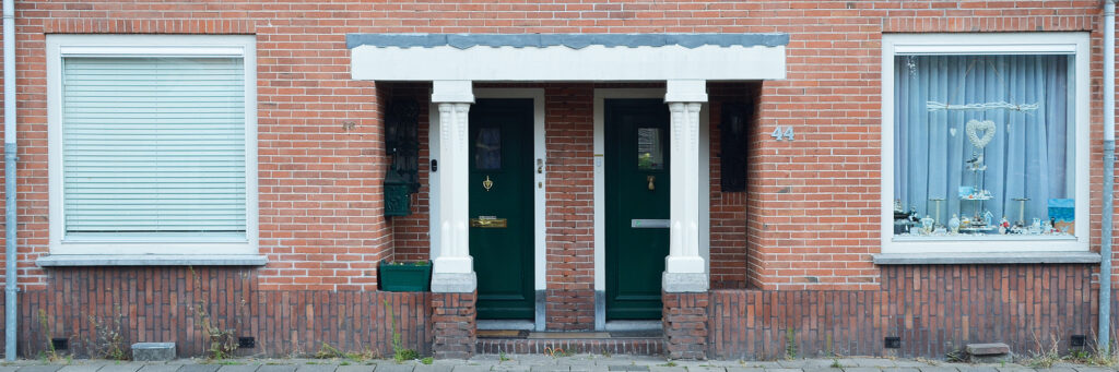 overkapping van de entree van twee woningen, de deuren zijn groen en de overkapping is wit