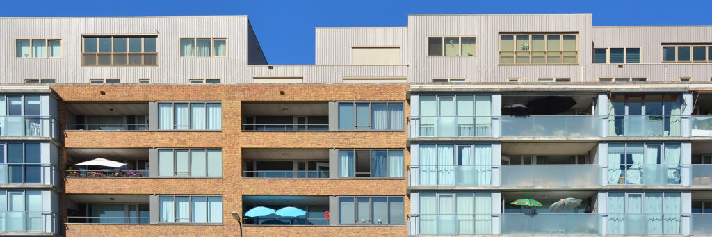 appartementencomplex met aan de linkerkant gebruik van beige stenen en rechts gebruik van glas en wit