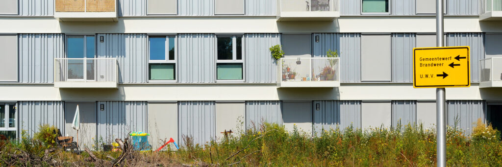 appartementen met balkonnetjes. het is grijs met wit en heeft aan de buitenkant een soort van golfplanten look