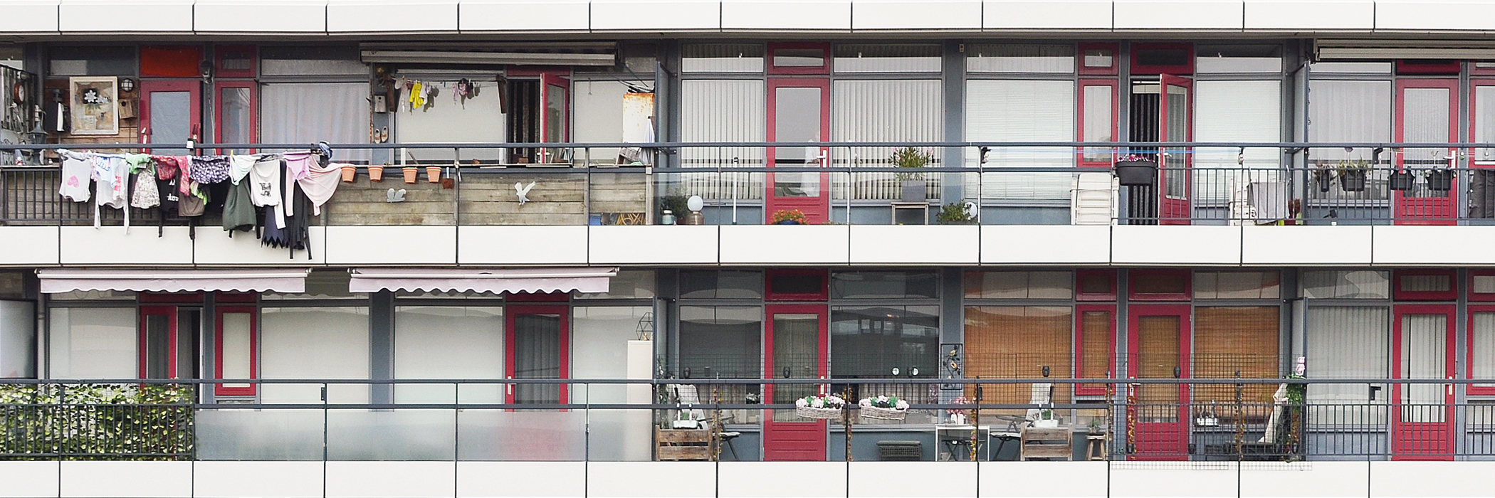 flat met rode deuren en ramen. de kozijnen zijn grijs. aan de railing hangt was te drogen