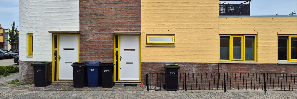 wonning die aan de rechterkant geel is met gele kozijnen. ze hebben witte deuren