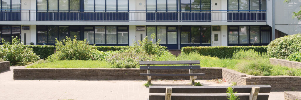 flatgebouw met een soort van binnenplein waar groen is en een gelegenheid om op een bankje te zitten