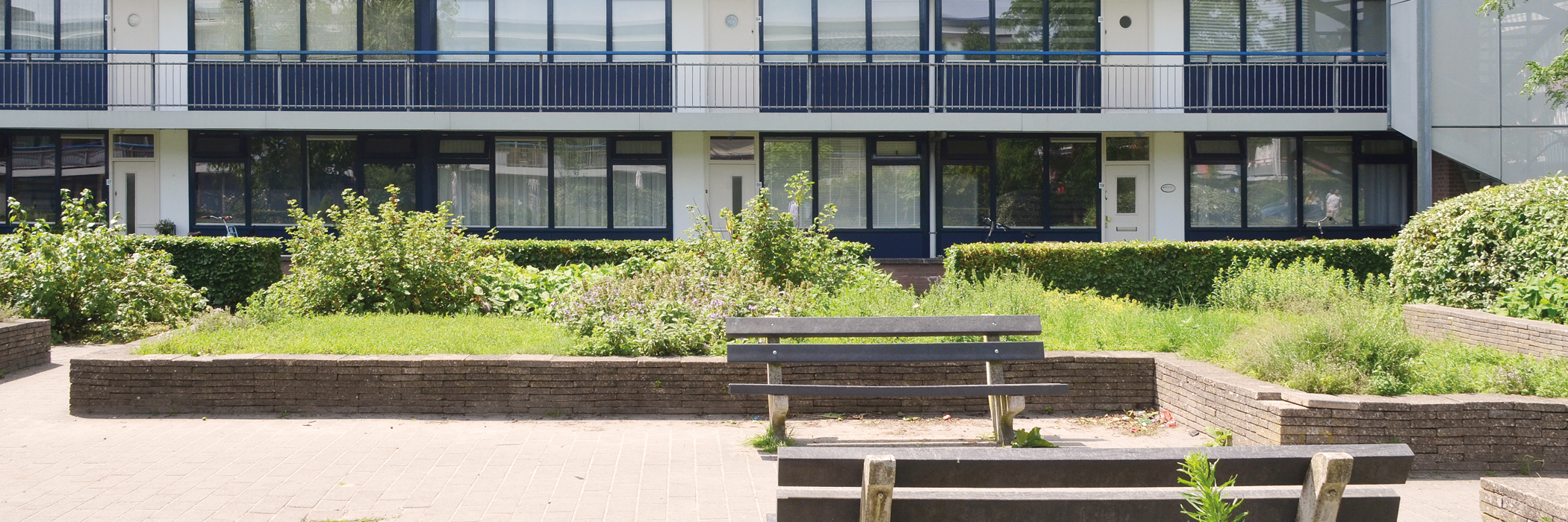 flatgebouw met een soort van binnenplein waar groen is en een gelegenheid om op een bankje te zitten