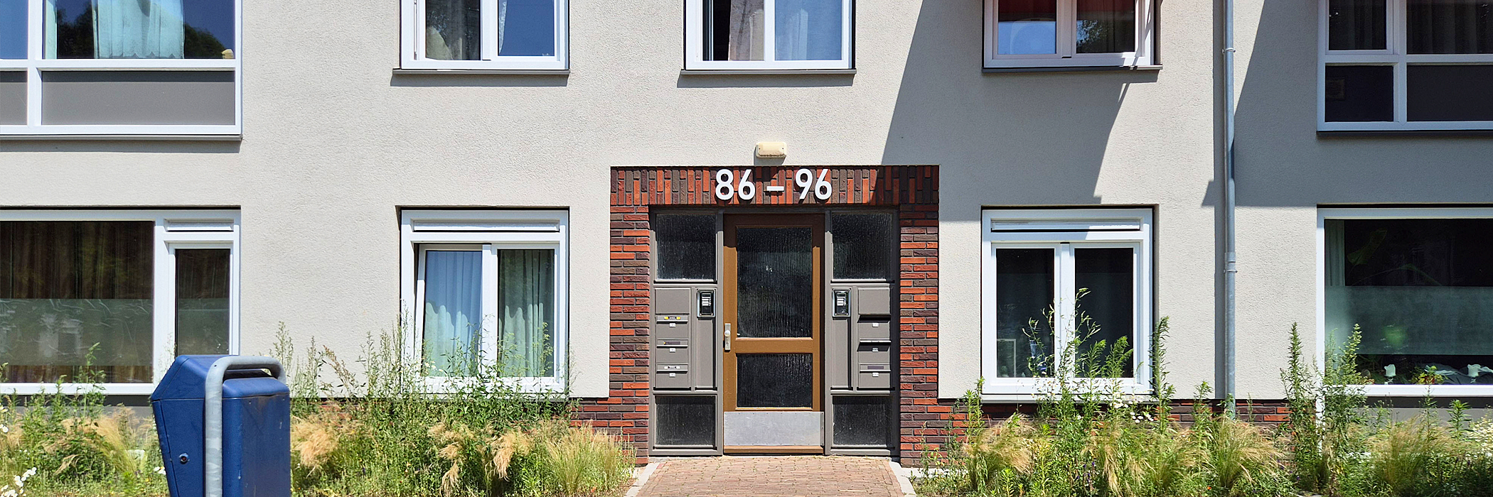 entree van een woningcomplex. boven de deur zijn huisnummers te zien