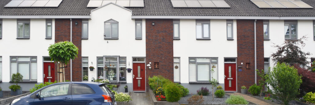 Witte woningen met rode deuren. de woningen hebben een mooie voortuin met groene planten