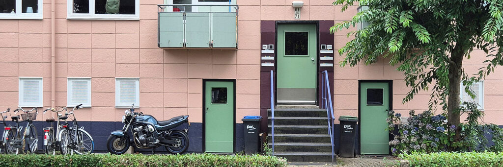 entree van een wooncomplex, voor de woningen staan fietsen en een motor geparkeerd