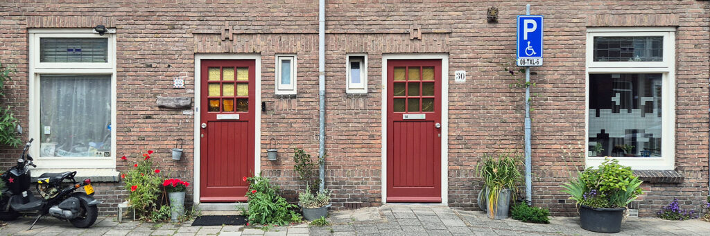 woningen met rode deuren. voor de deuren staan planten en een scooter