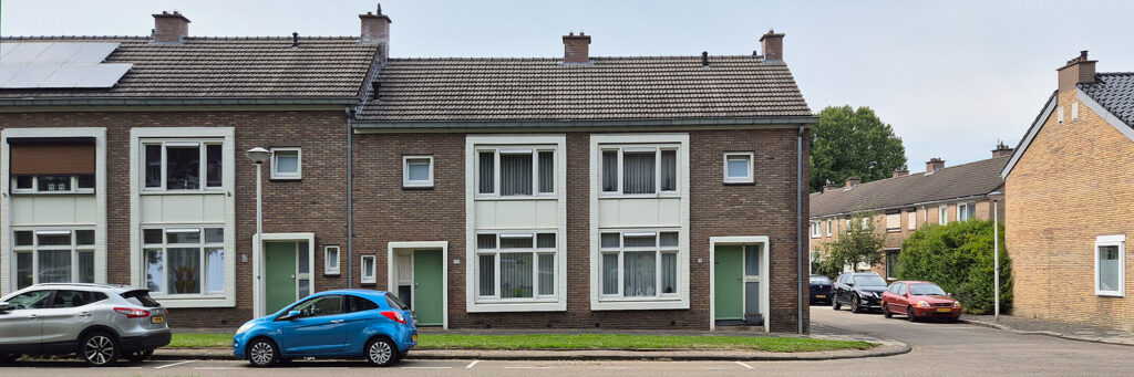 woning met grote kozijnen te hoogte van twee verdiepingen, de kozijnen zijn wit en de deuren zijn groen
