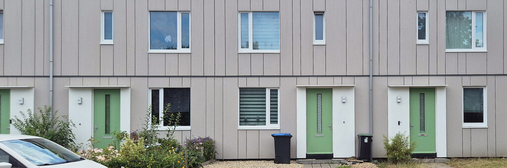 schakelwoningen in het grijs met groenen deuren en witte kozijnen