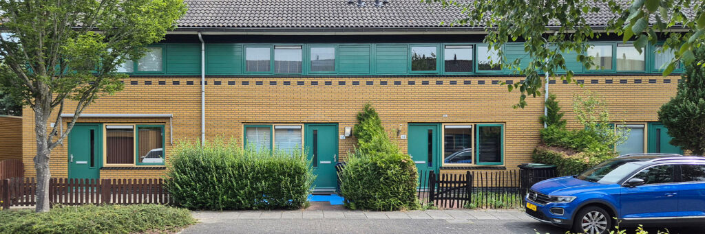 woningen met gele stenen. de deuren zijn groen en de bovenverdieping heeft ook een groenen strook