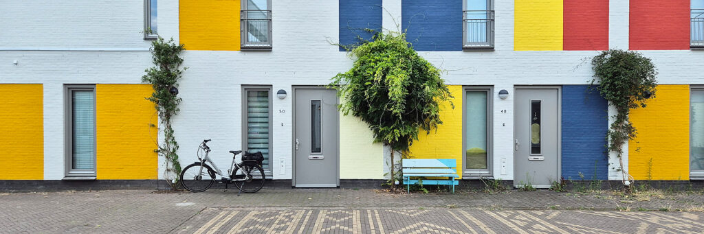 Woningen met grijze deuren. op de voorkant van het complex zijn er vakken geel, blauw en rood gemaakt