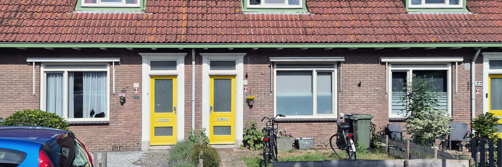 schakelwoning met gele deuren. gescheiden met een groenstrookje. in de tuin staan fietsen en containers