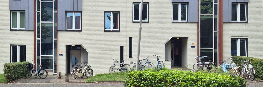entree van een woningcomplex, voor het complex staan overal fietsen geparkeerd