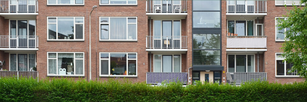 appartementencomplex met een groene struik ervoor
