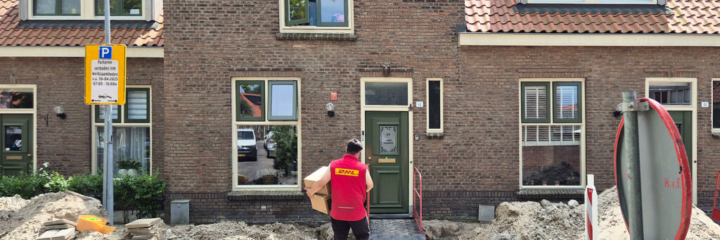 Woning waar de stoep open ligt. je ziet een pakketbezorger met een pakket in zijn handen